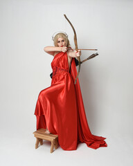 Full length portrait of  blonde model dressed as mythological fantasy goddess in flowing red silk...