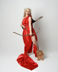 Full length portrait of  blonde model dressed as mythological fantasy goddess in flowing red silk...