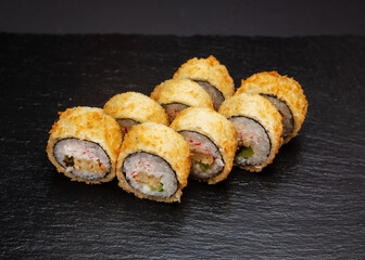 Sushi, rolls fried with tofu and crab meat. On a black background.