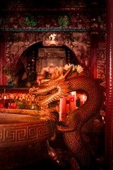 Burning prayer sticks fill the room with billowing smoke with dragon decorations on the sides at...