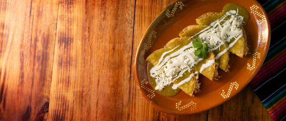 Green enchiladas. Typical Mexican dish made with a folded or rolled corn tortilla filled with shredded chicken and covered with spicy green sauce, cream, grated cheese and onion.