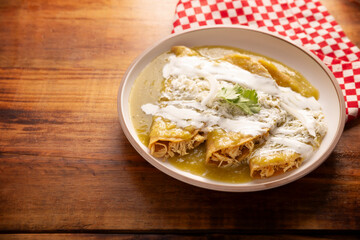 Green enchiladas. Typical Mexican dish made with a folded or rolled corn tortilla filled with shredded chicken and covered with spicy green sauce, cream, grated cheese and onion.