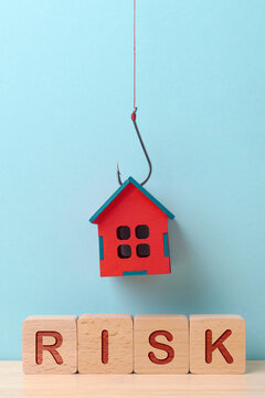A red house suspended on a fishing hook above the 'RISK' blocks