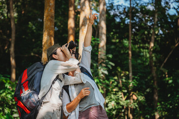 Fototapeta na wymiar woman family walking in the forest to watching a bird in nature, using binocular for birding by looking on a tree, adventure travel activity in outdoor trekking lifestyle, searching wildlife in jungle