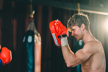 Active, athletes and fit men kick boxing and doing sport training workout in a gym. Two male partners or MMA boxer and trainer practice sparring exercises for a healthy wellness lifestyle.