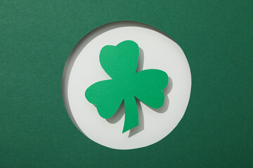 Green paper and clover on white background, top view