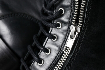 Black leather background. Grunge autumn clothing. Winter fashion texture. Closed fastener zipped zipper. Metal silver shiny zipper teeth background. Leather shoe background. Shoelaces closeup. © Paweł Michałowski