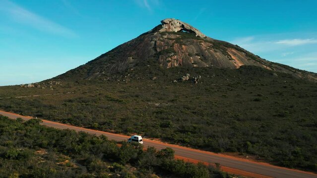 aerial of a van driving in front of frenchman peak in cape legrand national park near esperance on a sunny day, western australia