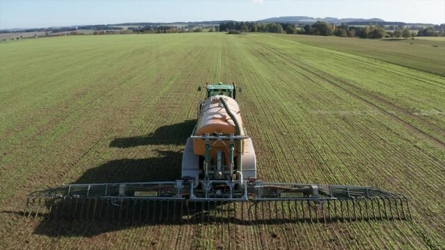 Liquid manure spreader releasing slurry on field aerial view