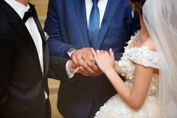 The male hand of the pope holds the hands of the bride and groom. Blessing of young people for the...