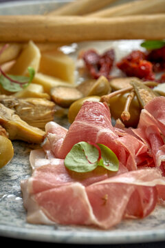 A plate of antipasti, artichokes, cheese, grisini and jamon cr