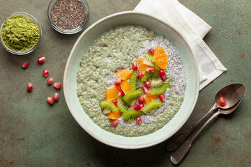 Matcha chia puddind with fruit berry salad in bowl on grey background. Healthy breakfast