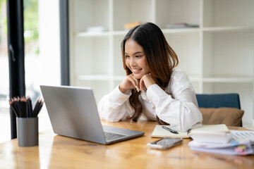 A young woman in a white shirt joins a video chat on Her laptop in a bright modern office.