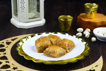 Baklava, one of Turkish dessert served on white plate. Middle east theme for ramadan month and breakfasting. Dark moody photo. 