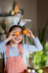 funny child girl playing with Easter eggs at table at home