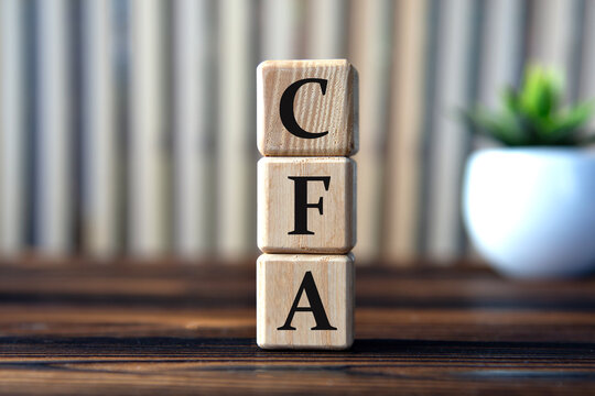 CFA - acronym on wooden cubes on the background of books and a cactus