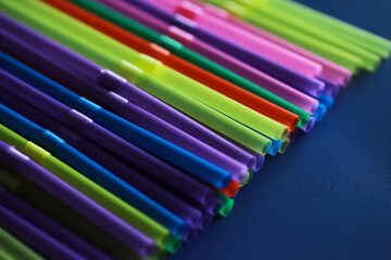 Colorful plastic drinking straws, close up as background. colored tubules for juice and cocktails on black wooden table - obrazy, fototapety, plakaty
