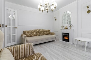Interior in light colors with a bio fireplace, illuminated by burning sconces on the wall