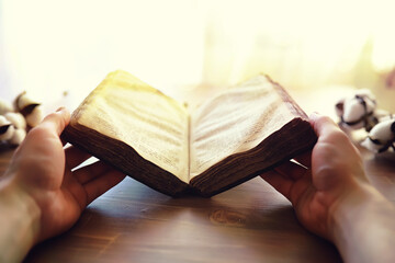 Praying with hand on bible black background. An old book with yellowed pages. Second-hand books.
