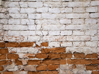 Old brick wall with peeling paint and bricks crumbling from time