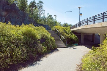 Asphalt coated walkway going under concrete bridge in sunny summer weather.