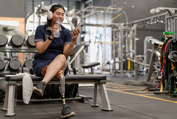 Fototapeta na wymiar Confident woman with artificial leg exercising in fitness gym. Prosthetic limb strengthen physical injury amputee. Accident survivor with mechanical prosthesis leg workout for wellbeing body mobility.