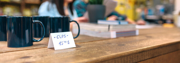Close up of blue breakfast mugs for retail sale over wooden counter in vintage shop