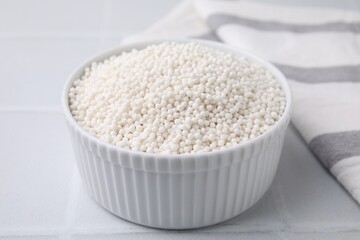 Tapioca pearls in bowl on white tiled table, closeup
