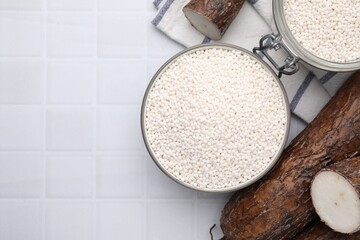 Tapioca pearls and cassava roots on white tiled table, flat lay. Space for text