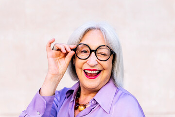 portrait of nice senior woman in glasses smiling and winking looking at camera, concept of elderly...
