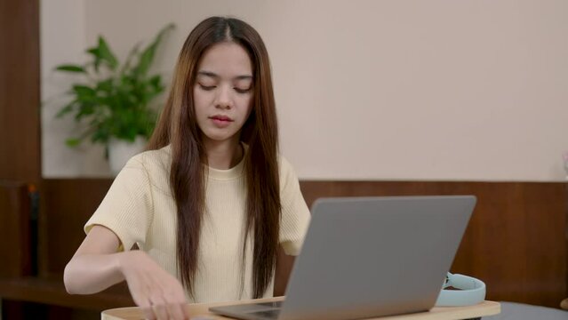 Asian woman sitting in front laptop computer desk, woman ordering online on social media, woman takes out credit card enters card information into payment terminal, deduct credit card.