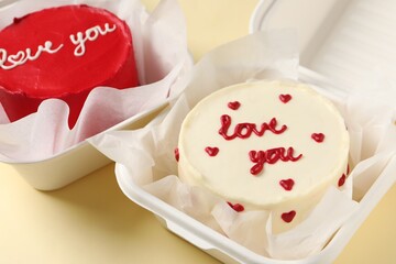 Bento cakes in takeaway boxes on beige table, closeup. St. Valentine's day surprise