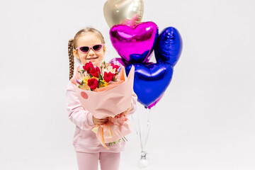 Happy little girl on a light background in her hands with a bouquet of flowers. Concept for party, holidays, flower bouquets and happy emotions.