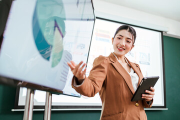 Portrait of a smart Asian young entrepreneur businesswoman using her digital tablet while standing...