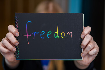 Kolorowy napis freedom napisany na kartce i trzymany w dłoni przez kobietę  - obrazy, fototapety, plakaty