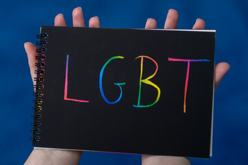 Tęczowy napis LGBT trzymany na kartce w dłoniach  - obrazy, fototapety, plakaty