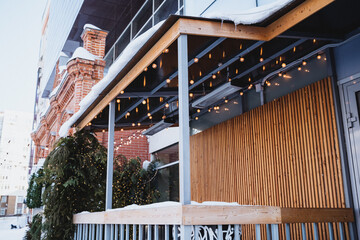 Modern outdoor restaurant seating with wooden slats, string lights, and inviting ambiance.