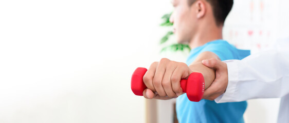 Doctor or Physiotherapist helping man exercise with dumbbell and physical therapy help for muscle...