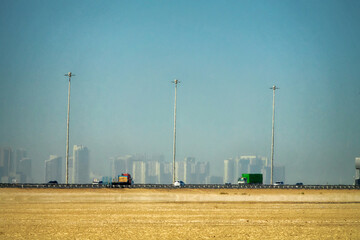 Desert city. Through the desert mirage, heat haze emerges the modern city with high-rise buildings...