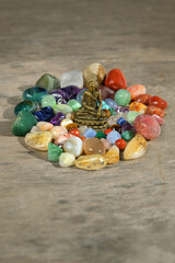 colorful quartz minerals and Buddha figurine on wooden background. set of different gemstones for...