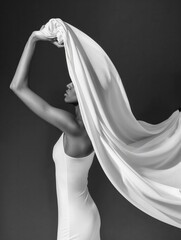 Elegant monochrome portrait of a woman with flowing fabric, capturing a moment of grace and fluid motion