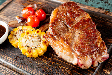 Grilled Ribeye Steak on wooden board, prime cowboy steak on dark background