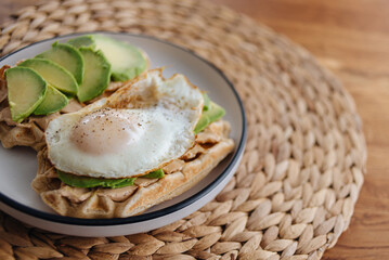 waffles with cottage cheese, avocado and eggs in a plate on a wooden table, healthy and satisfying breakfast