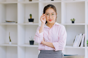 Fototapeta na wymiar Happy asian young businesswoman arms crossed standing in office working space.