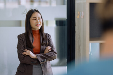 Happy asian young businesswoman arms crossed standing in office working space.