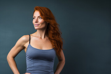 Ambitious Redhead: Determined Fitness Enthusiast Stands Strong Against Dark Background with Copy Space
