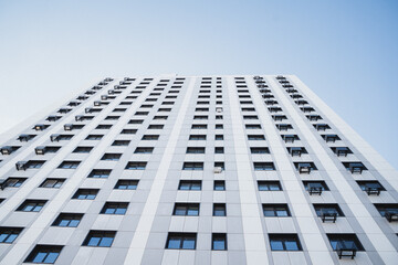 Modern residential building with square windows and air conditioning units under a clear blue sky.
