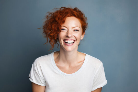 Happy 40-Year-Old Woman with Curly Short Hair Laughing in White T-Shirt against Dark Blue Background