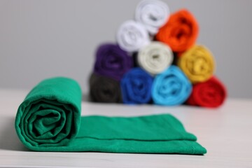 Sorting and organizing. Different rolled clothes on white wooden table, closeup