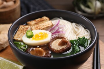 Delicious vegetarian ramen in bowl on wooden table, closeup
